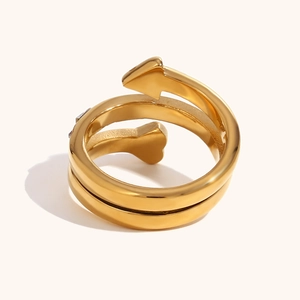 Macro detail of 18K gold-plated spiral ring featuring arrow and heart-shaped ends