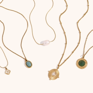 Détail de colliers plaqués or avec pendentifs perle, marbre et motif soleil gravé