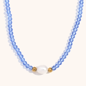 Vue macro de perles de cristal bleu ciel et une perle d'eau douce sur collier en or 18K