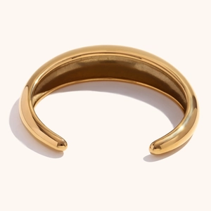 Primer plano de un brazalete abierto grueso de acero inoxidable chapado en oro de 18K