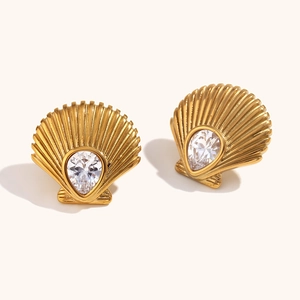 Macro detail of 18K gold-plated shell earrings with pear-cut zircon and ocean-inspired texture