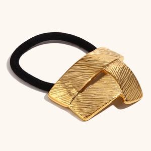 Detailed macro view of 18K gold plated metal geometric fold charm on black hair tie