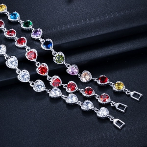 Detail von drei Herzschliff-Zirkonia-Armbändern in bunten Farben auf dunklem Grund