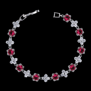 Détail d'un bracelet en zircon avec pierres rouges rondes et trèfles argentés polis