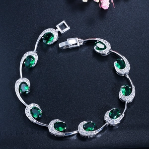 Detailopname van een zilveren armband met smaragdgroene stenen en zirkonia kristallen