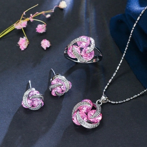 Vue macro de parure bijoux en argent avec zircons roses et design de tourbillon serti