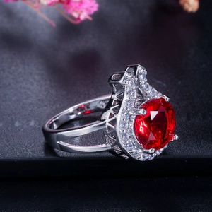Detail eines Silberrings mit facettiertem rotem Edelstein und funkelnden Zirkonias