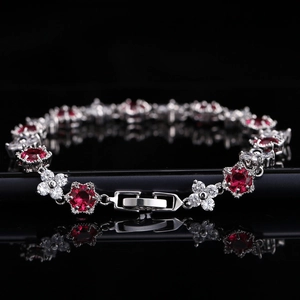 Détail macro du bracelet style rubis rouge avec trèfles en zircon sur fond noir