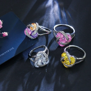 Détail macro de quatre bagues argentées avec zircons colorés et sertissage en spirale