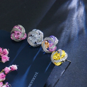 Macro de boucles d'oreilles fleurs en zircon rose, jaune et violet sur support bleu chic