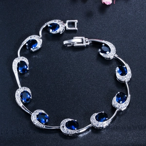 Elegante zilveren armband met ovale blauwe saffieren en CZ-stenen op een zwarte achtergrond