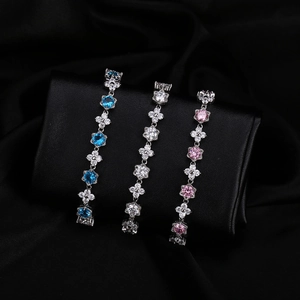 Détail de bracelets argentés aux motifs floraux et zircons multicolores sur fond noir