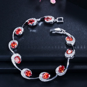 Detail van zilveren armband met rode ovale edelstenen en sprankelende zirkoon pavé