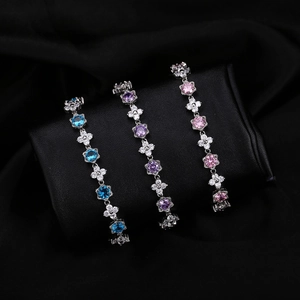 Détail de bracelets en zircon floral bleu clair, violet et rose sur un coussinet noir