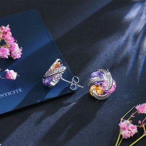 Gros plan de boucles d'oreilles spirales avec zircons colorés sur fond bleu élégant