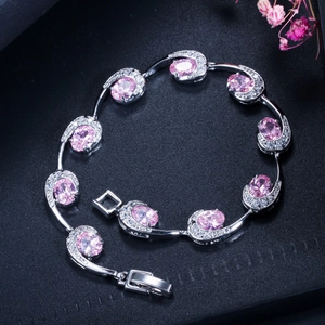 Detail van zilveren armband met druppelvormige roze edelstenen en zirkonia-accenten