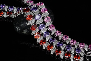 Detail of leaf-shaped silver bracelets with oval red, purple, and pink gemstones