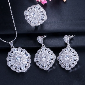 Detailed view of silver flower jewelry set with sparkling crystals on black texture
