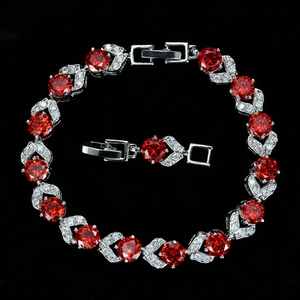 Primer plano de pulsera plateada con circón rojo y detalle del cierre desplegable