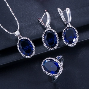 Detail of jewelry set with oval dark blue stones and beaded silver edges on dark background