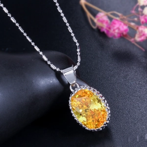 Detailed view of an oval yellow zircon pendant necklace on a dark natural stone base