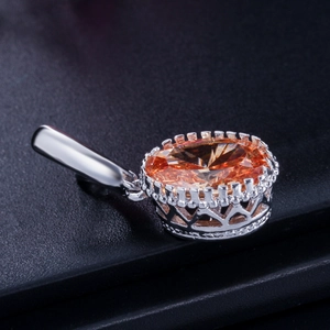 Macro shot of silver pendant with oval orange gemstone and crown hollow carvings