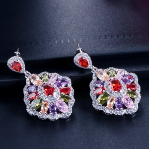 Macro shot of colorful gemstone drop earrings with red ruby center and silver setting