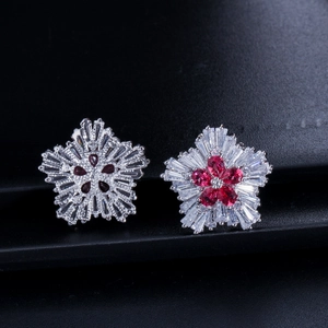 Detailed view of silver flower stud earrings with red gemstones and clear crystals