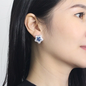 Close-up of snowflake zircon stud earrings with blue stones on model ear