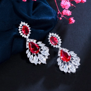 Macro detail of silver-tone drop earrings with vibrant red pear-shaped gemstones