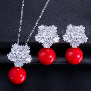 Dettaglio macro del set gioielli sposa a fiocco di neve con perle rosse e zirconi