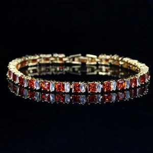 Gros plan d'un bracelet doré orné de zircons rouges carrés et baguettes blanches