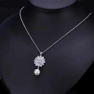 Detailansicht der Blumenkette mit Zirkonia und Perle auf einem schwarzen Schmuckständer