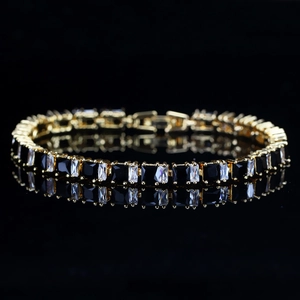 Gros plan d'un bracelet tennis plaqué or avec zircons noirs et clairs rectangulaires