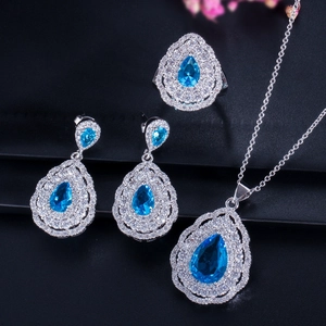 Macro shot of blue pear-cut jewelry set with necklace, earrings, and ring on black background