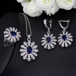 Détail d'un ensemble de bijoux floraux avec pierres bleues ovales et zircons blancs