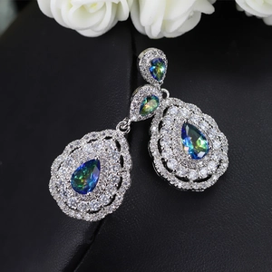 Macro shot of silver drop earrings with iridescent gems on a black leather stand