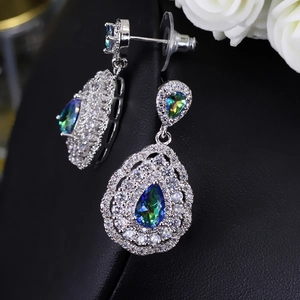 Macro detail of teardrop earrings featuring rainbow stones and zircon paving on black leather