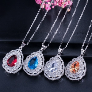 Detailed view of pear-cut halo pendants in ruby red, royal blue, clear, and champagne colors
