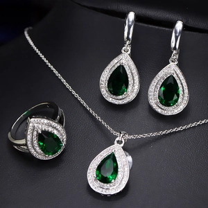 Macro shot of silver jewelry set with pear-cut green gemstones and white zircon halo