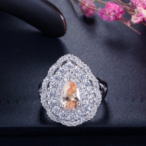Detailed view of champagne pear-cut gemstone ring with triple halo zircon setting