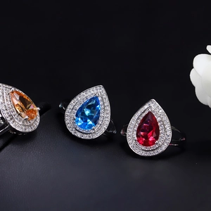 Macro detail of pear-cut zircon rings in orange, blue and red with halo setting