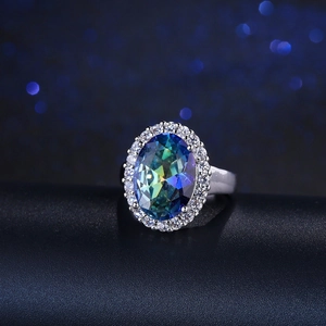 Detalle de anillo con gema ovalada verde azulado y halo de circonitas en plata