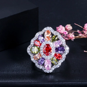 Bague cocktail florale avec pierre centrale rouge et pierres précieuses colorées sur fond noir