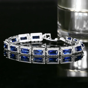 Détail d'un bracelet de luxe argenté avec zircons bleus rectangulaires et halo de diamants