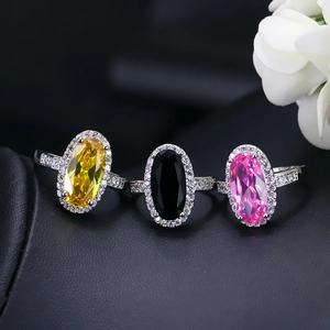 Detailed view of oval zircon rings in yellow, black, and pink with halo stones