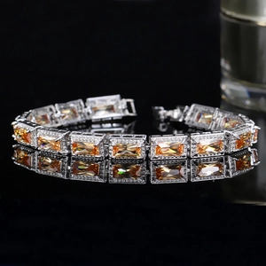 Détail d'un bracelet de luxe avec pierre orange taille émeraude sur surface noire