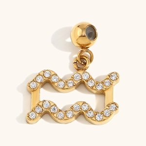 Macro detail of 18K gold plated Aquarius constellation pendant with white zircon stones