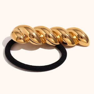 Detailed shot of black elastic hair tie featuring a polished 18K gold-plated twisted metal decor