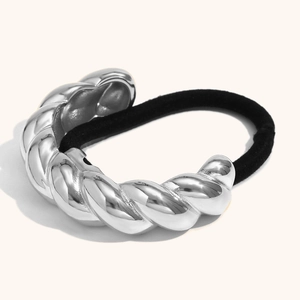 Élastique à cheveux en métal argenté torsadé poli avec élastique noir sur fond beige